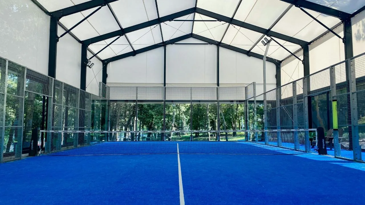 Indoor covered padel court with blue artificial turf