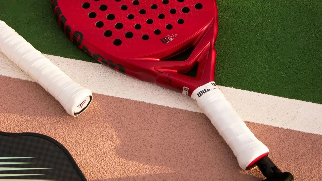 Wilson padel racket with white overgrip wrapped on court surface