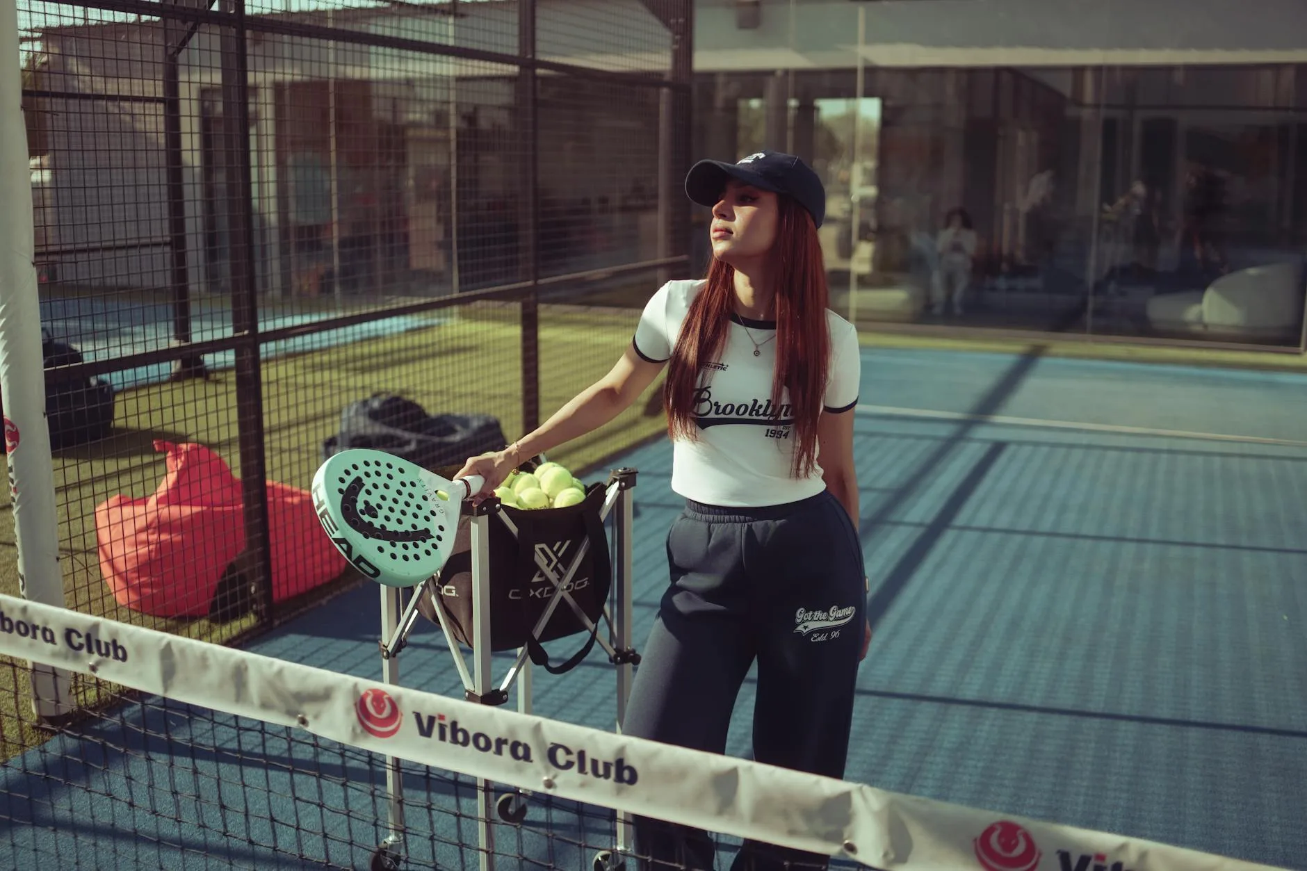Padel player holding a perforated racket on a glass-walled court