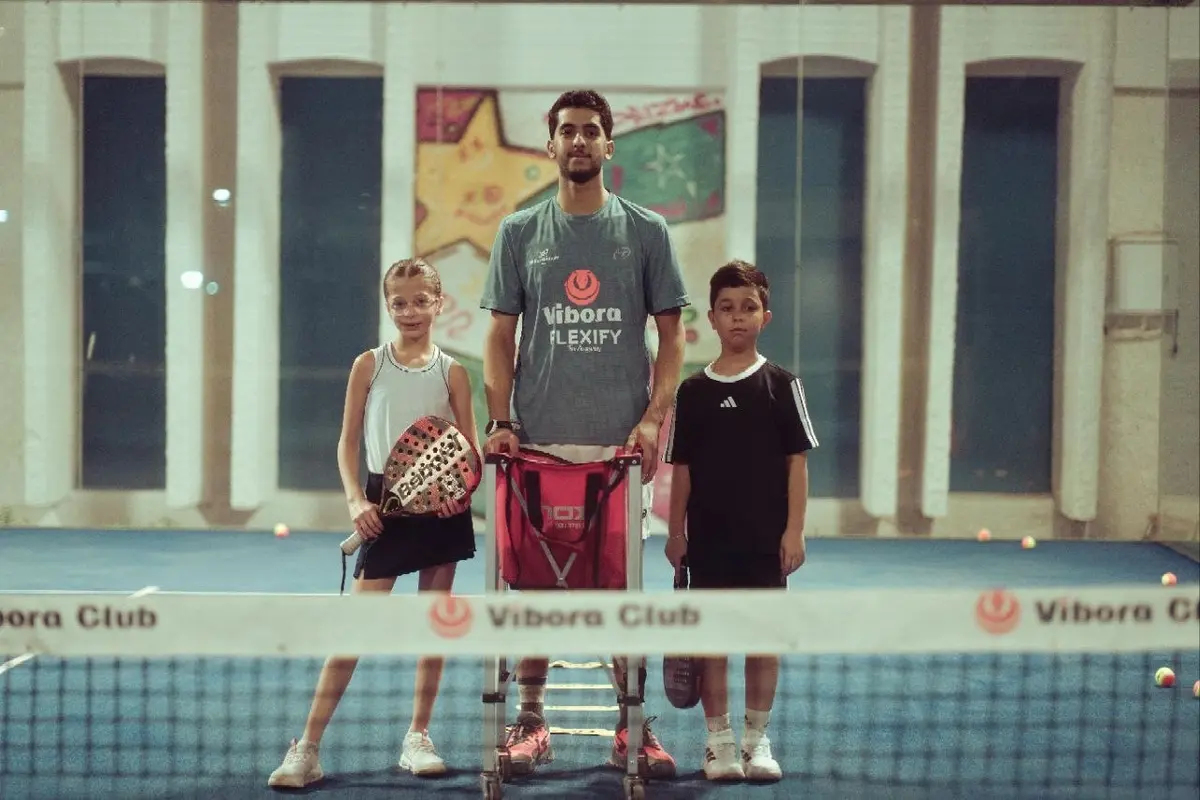Padel coach standing with two young players at a Vibora padel club