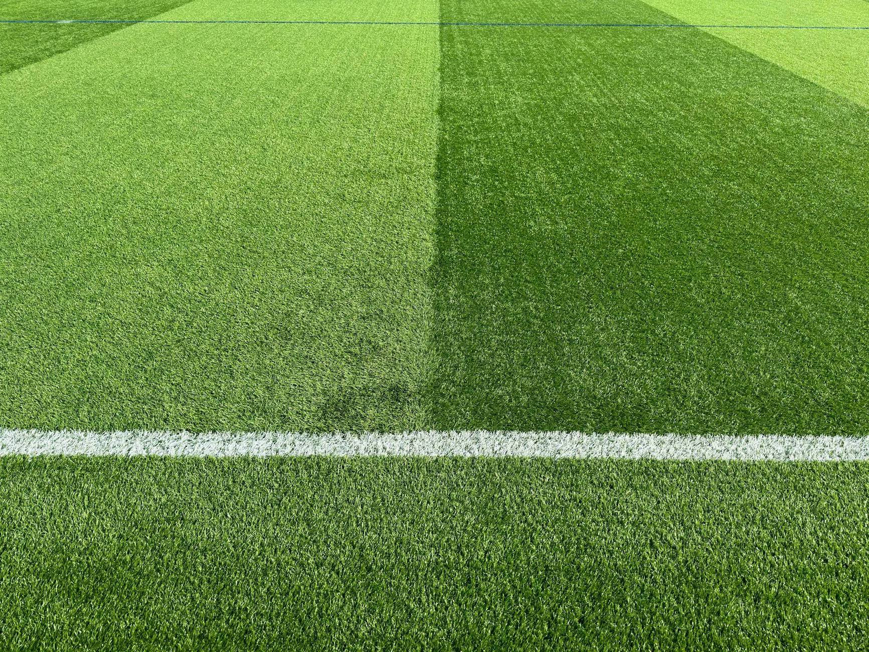 Sand infill visible between artificial grass fibres on a sports court