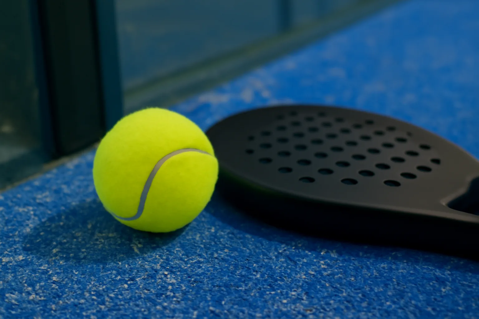 Padel ball near the glass wall after bouncing on court