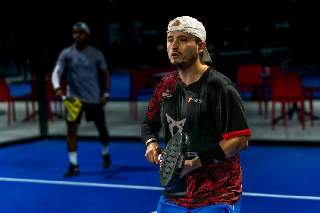 Padel balls on a padel court beside a racket and glass wall