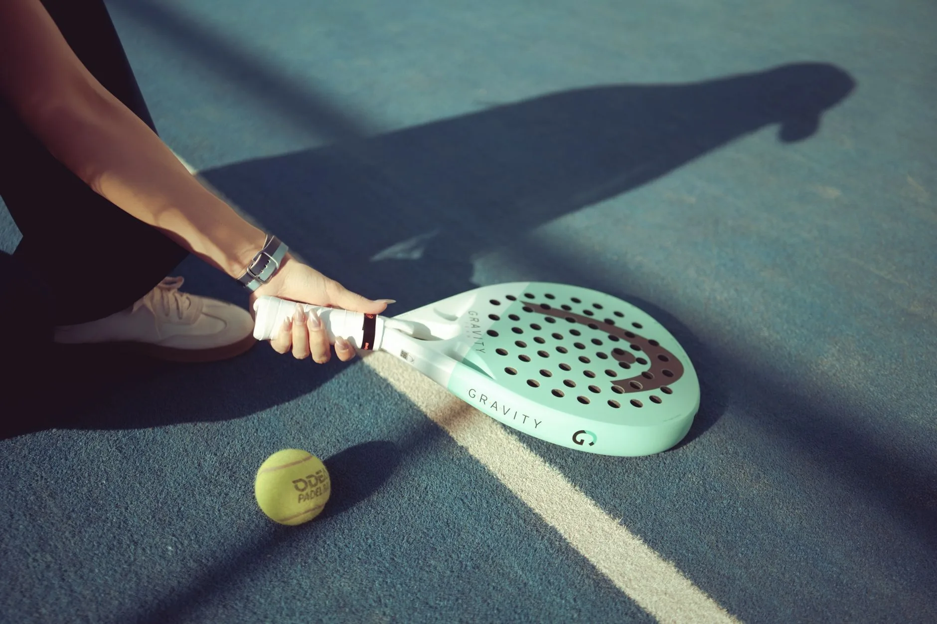 Perforated padel racket and ball on a blue court