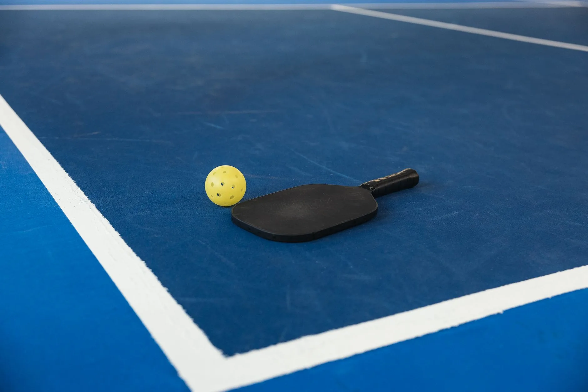 Pickleball paddle and ball on a court surface